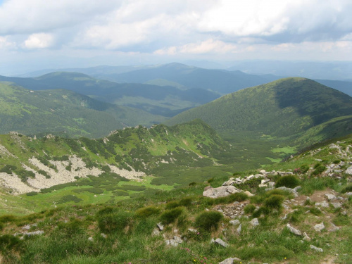 W tle Kukul /1540m/ i Koźmieska, ciąg dalszy grani czarnohorskiej, o kilkaset metrów niższy, biegnący od Howerli ku Przełęczy Tatarskiej. Bliżej pasemko Wielkich Kozłów i Homuł /1786m/, doskonały punkt widokowy.