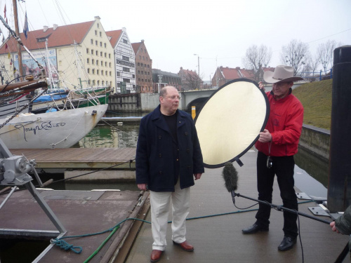 Kris Kamiński udziela wywiadu, w tle s/y Josef Conrad