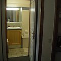 Łazienka - widok z korzytarzyka, po prawej widoczna wanna z prysznicem.